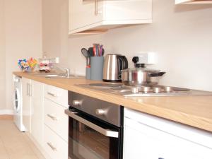 a kitchen with white cabinets and a stove top oven at The Otton Suite in Dungannon