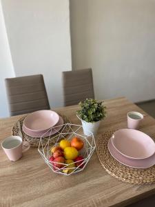 a wooden table with plates and a basket of fruit at Penzion Brtnice in Brtnice