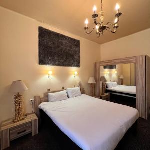 a bedroom with a large white bed and a chandelier at Grand Hôtel de Valenciennes in Valenciennes +36 photos