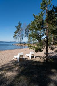 two white chairs sitting on a beach near the water at Utula Nature Retreat in Ruokolahti