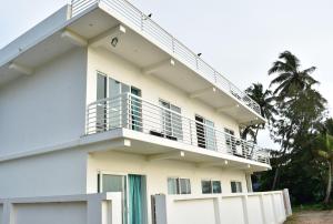 een wit huis met een balkon en palmbomen bij Asthamaya Beach Homestay in Alleppey