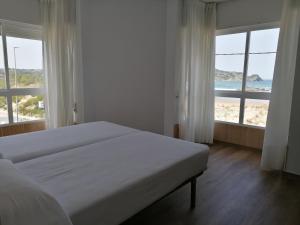 a bedroom with a bed with a view of the beach at Apartamentos Regollera Premium con garaje in Noja +145 photos