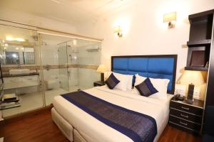 ein Schlafzimmer mit einem großen Bett und einer Dusche in der Unterkunft Hotel Capitol Hills - Greater Kailash Delhi in Neu-Delhi