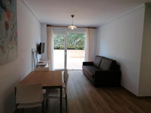 sala de estar con sofá, mesa y ventana en Apartamentos Regollera Premium con garaje, en Noja