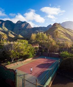 a man on a tennis court with mountains in the background at Redondo de Guayedra in Guayedra