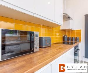 a kitchen with a microwave and a wooden counter top at ByEvo Darwin House - Contractor pad or Family getaway - Close to Thonock Park Golf Course in Gainsborough