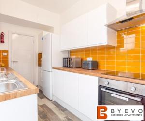 a kitchen with white cabinets and an orange tiled wall at ByEvo Darwin House - Contractor pad or Family getaway - Close to Thonock Park Golf Course in Gainsborough
