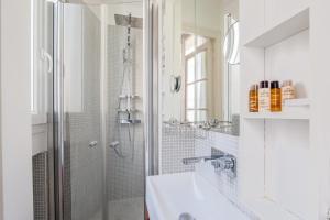 a white bathroom with a shower and a sink at Veeve - Impressions of the Eiffel Tower in Paris