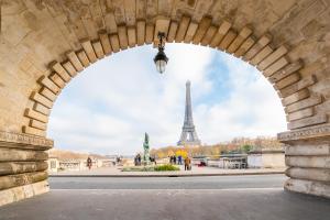 an archway with the eiffel tower in the background at Veeve - Impressions of the Eiffel Tower in Paris