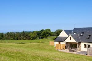 a house with a large grassy field next to it at Beech Cottage at Williamscraig Holiday Cottages in Linlithgow