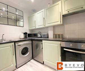 a kitchen with white cabinets and a washing machine at ByEvo 19 Walker - perfect for contractors - close to GLA in Paisley