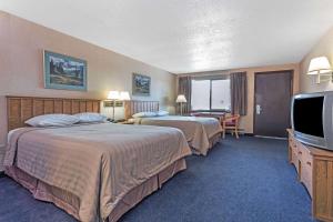 a hotel room with two beds and a flat screen tv at Travelodge by Wyndham Pioneer Villa in Halsey