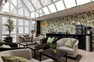 eine Hotellobby mit Sofas, Tischen und einer Fensterwand in der Unterkunft Best Western Plus Edward Hotel in Lidköping