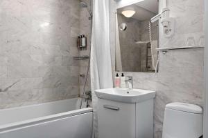 a bathroom with a toilet and a sink and a tub at Best Western Plus Edward Hotel in Lidköping
