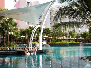 two men sitting in a swimming pool at a resort at Premier Residences Phu Quoc Emerald Bay Managed by Accor in Phú Quốc