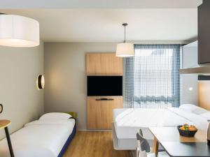 sala de estar con 2 camas y comedor en Aparthotel Adagio access Palaiseau Saclay, en Palaiseau