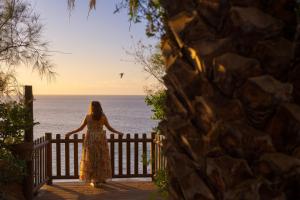 a woman standing on a fence looking out at the ocean at Redondo de Guayedra in Guayedra