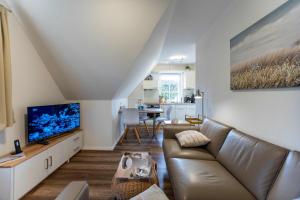 a living room with a couch and a tv at Ferienwohnung Klintum in Oldsum