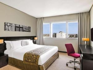 a hotel room with a bed and a desk and window at Mövenpick Hotel Casablanca in Casablanca