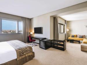 Cette chambre comprend un lit, un bureau et un canapé. dans l'établissement Mövenpick Hotel Casablanca, à Casablanca