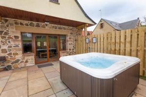 una gran bañera de hidromasaje en un patio junto a un edificio en Laurel Cottage at Williamscraig Holiday Cottages, en Linlithgow