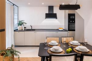 una cocina con mesa y sillas y una cocina con armarios blancos. en Magno Apartments Robles with Bath Tub and Private Parking, en Sevilla