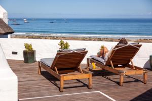 Abalone Hotel & Villa's في باتيرنوستير: امرأة مستلقية على كرسيين على الشاطئ