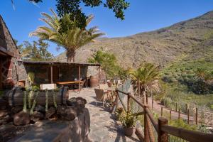 a house with a patio with palm trees and a mountain at Redondo de Guayedra in Guayedra