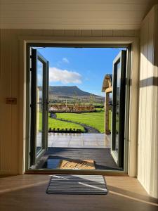 une porte ouverte sur une terrasse avec vue. dans l'établissement Shepherds Huts at Ballyness Farm, à Dungiven