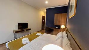 a bedroom with a white bed and a television at Point Hotel Tbilisi in Tbilisi City