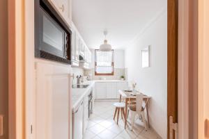 cocina blanca con fregadero y mesa en Cœur de ville - Au pied du métro - 3 chambres, en Bobigny