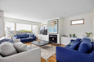 sala de estar con sofás azules y chimenea en Dana Beach House, Blairgowrie, en Blairgowrie