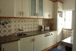 a kitchen with white cabinets and a sink at Casa Alberto in Portimão