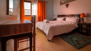 1 dormitorio con 1 cama grande, escritorio y ventana en Hotel Rayyan l 'Escale, en Ouarzazate