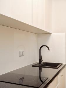 eine Küche mit einem schwarzen Waschbecken und weißen Schränken in der Unterkunft Prymasa Tysiąclecia 83A (D) by Perfect Apart in Warschau