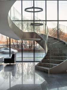 una escalera de caracol en un edificio de cristal con una silla en Prymasa Tysiąclecia 83A (D) by Perfect Apart, en Varsovia