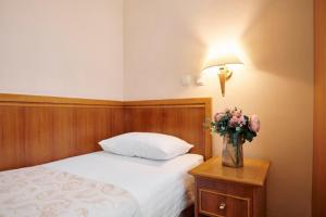 a bedroom with a bed and a table with a vase of flowers at Hotel Lovran in Lovran