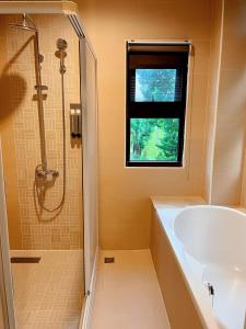 baño con bañera, lavabo y ventana en Landay Homestay, en Yilan City