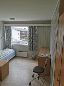 モルデにあるMolde Vandrerhjem Hostelのデスク、ベッド、椅子が備わる小さな客室です。