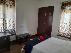 a bedroom with a bed and a table and windows at New Dream Homestay in Guwahati