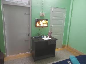 Zimmer mit einem schwarzen Schreibtisch und einem TV an der Wand in der Unterkunft New Dream Homestay in Guwahati
