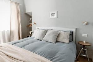 a bedroom with a bed with grey sheets and pillows at Lindhouse - Country House a Govone in Govone