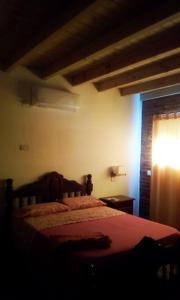 1 dormitorio con 1 cama con manta roja y ventana en El Candil en San Andrés de Giles