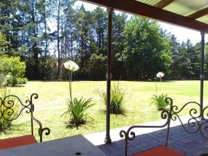 a porch with a table and chairs and a field of grass at El Candil in San Andrés de Giles