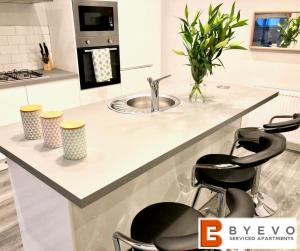 a kitchen with a sink and two bar stools at ByEvo Almar Villa - Comfy Contractor or Large groups property in Glasgow
