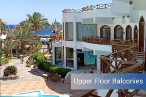 Red Sea Relax Hotel في دهب: مبنى ابيض كبير مكتوب عليه موازين الدور العلوي