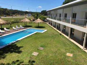 an outdoor swimming pool with chairs and umbrellas next to a building at Hotel Portezuelo in Punta del Este