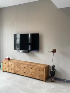 uma televisão numa parede com uma cómoda de madeira em Rooms Homestay em Hualien