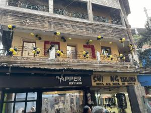 a building with a balcony with a woman on it at Sun India Guest House in Howrah