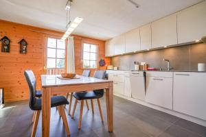 uma cozinha com uma mesa de madeira e algumas cadeiras em Chumma 22 em Riederalp